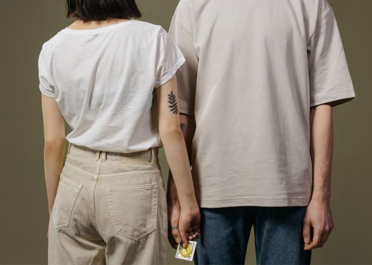 Male and female holding a condom