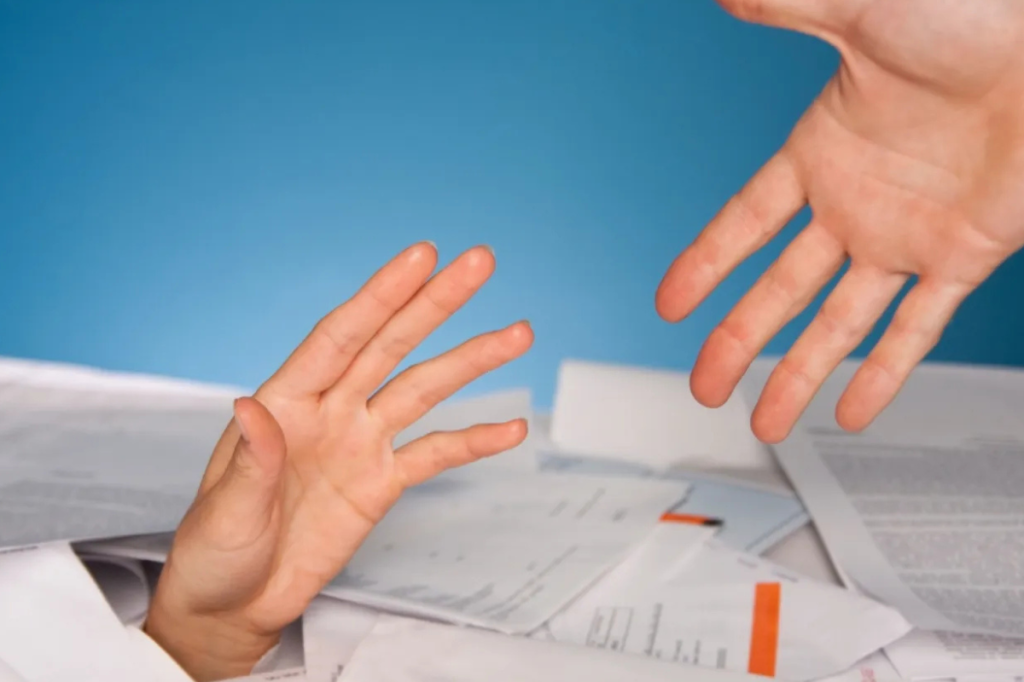 person reaching through unpaid bills to hold another hand for support
