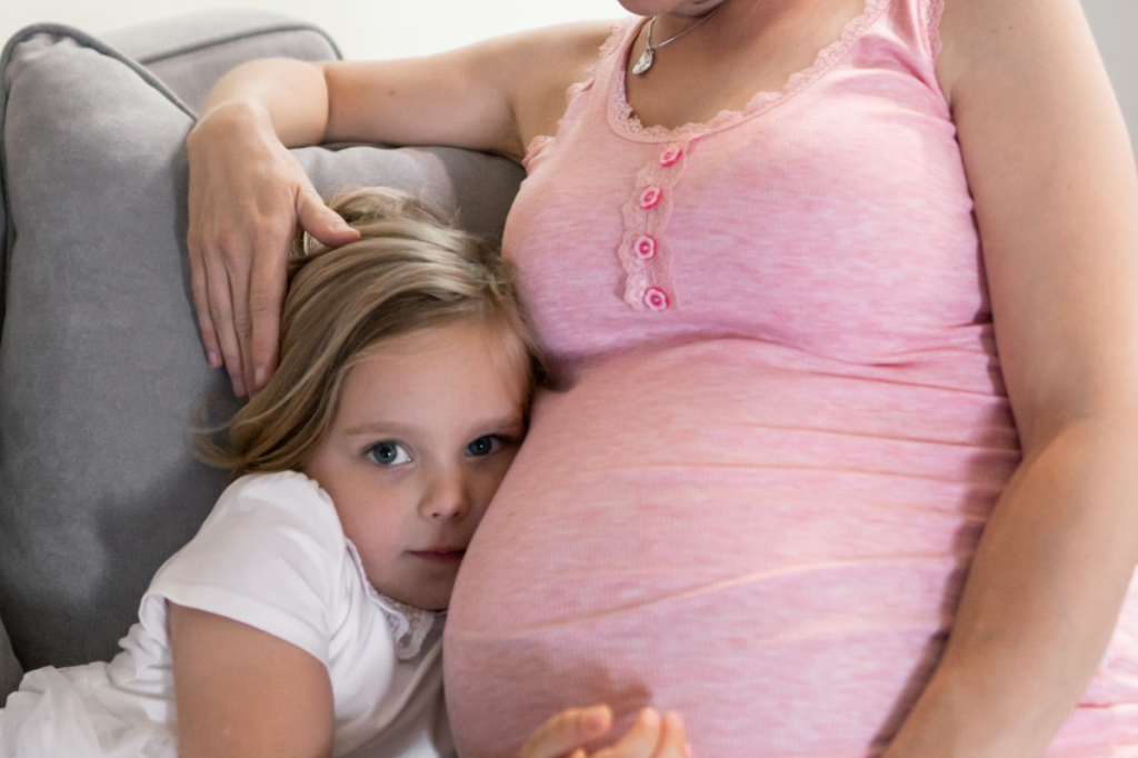 Child cuddling up to a pregnant woman.