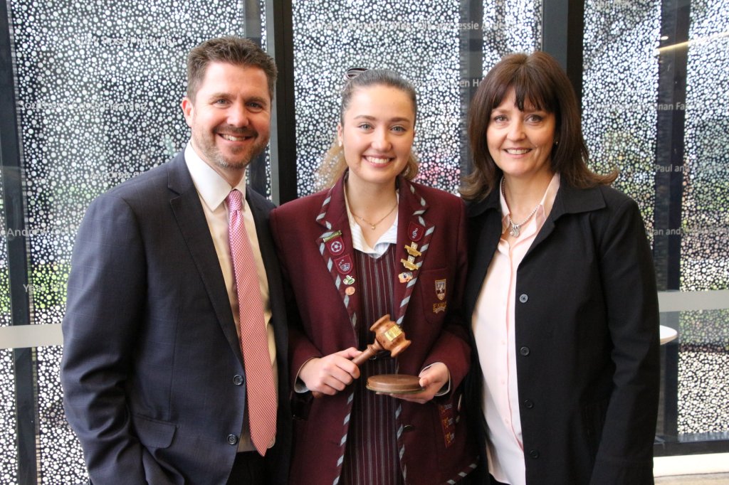 Young Lucy Stevens standing with two adults during her school days.
