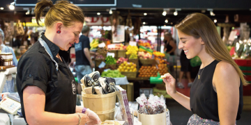 Woman tasting fresh produce while browsing stalls at Adelaide Central Market