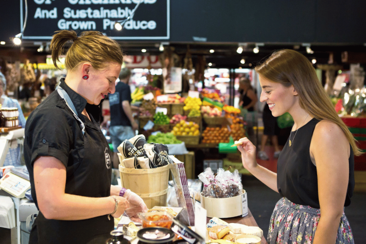 Woman tasting fresh produce while browsing stalls at Adelaide Central Market