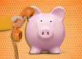 piggy bank with large phone pressed to its ear by a hand