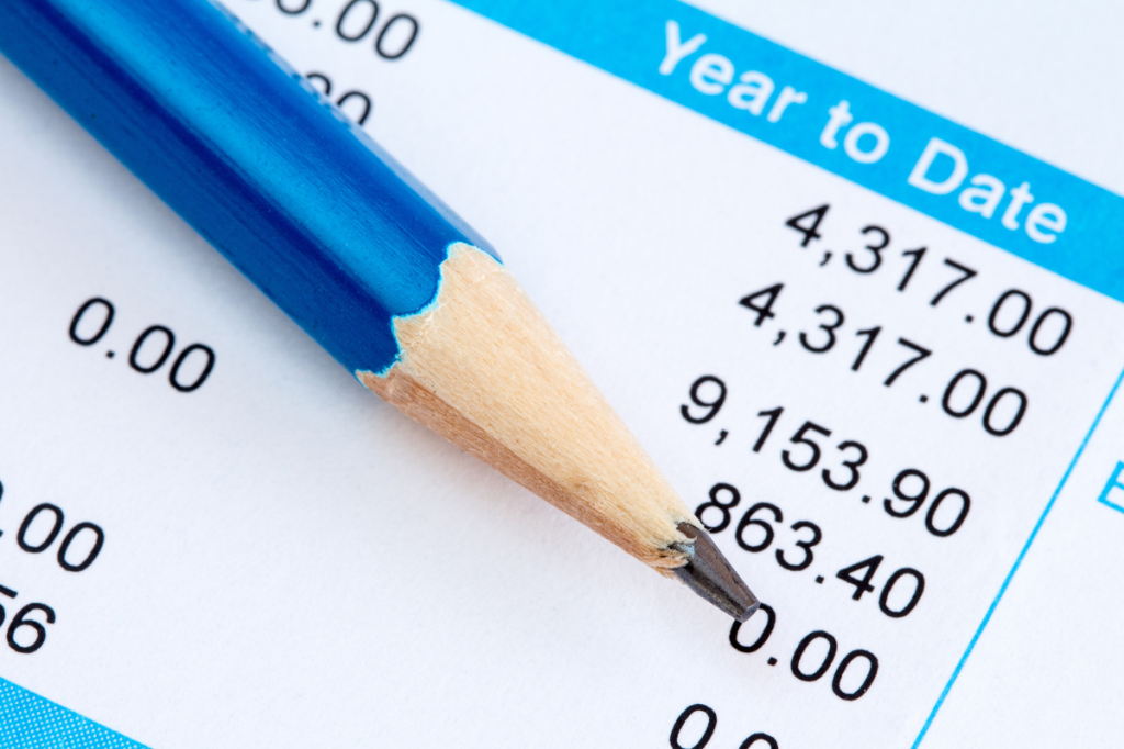 Close-up of a pay statement with a pencil pointing to year-to-date figures and a list of numbers.