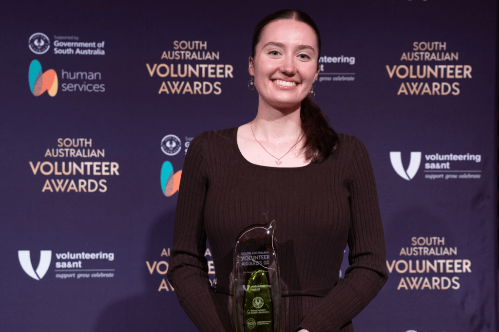 Lucy Stevens holding Young Volunteer of the Year award at ceremony
