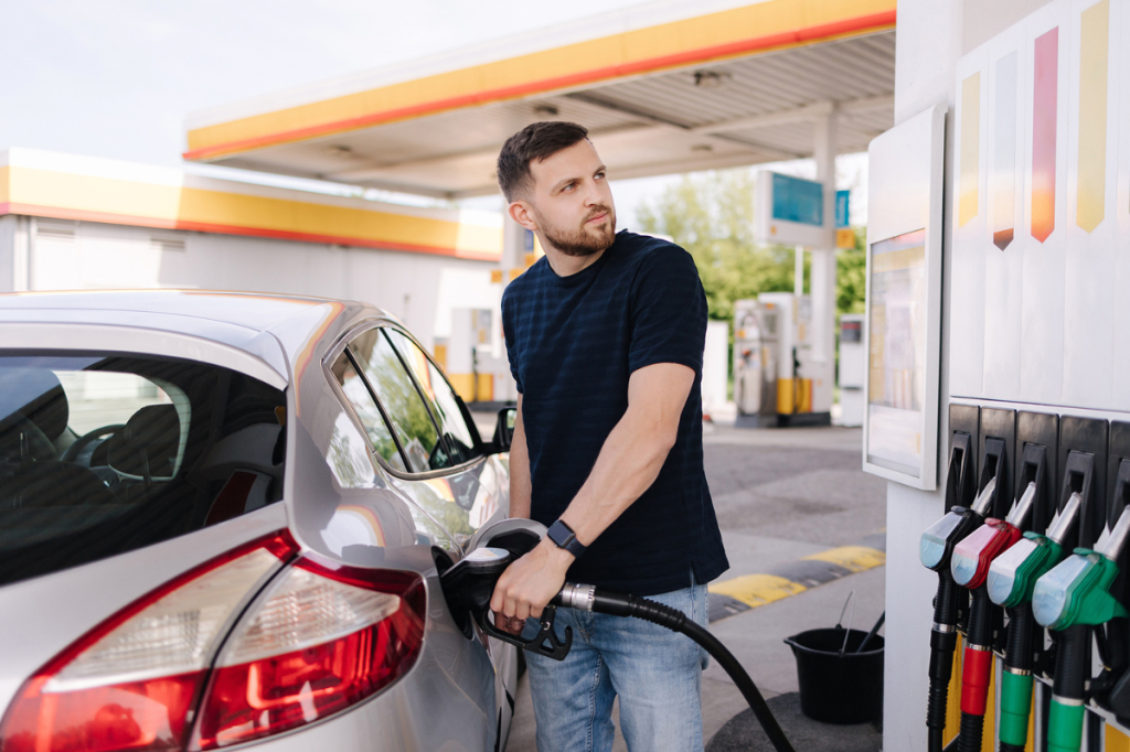 Young South Australian filling his car with fuel and looking worried.
