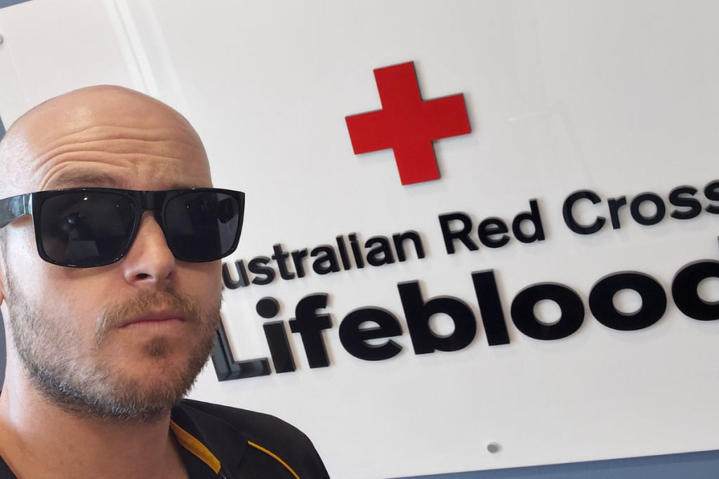 Brett in front of the Australian Red Cross Lifeblood sign.