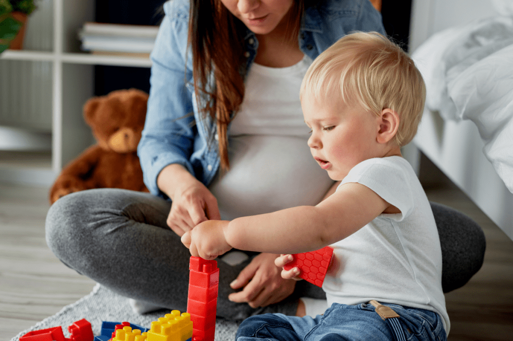 Pregnant woman playing with toddler.