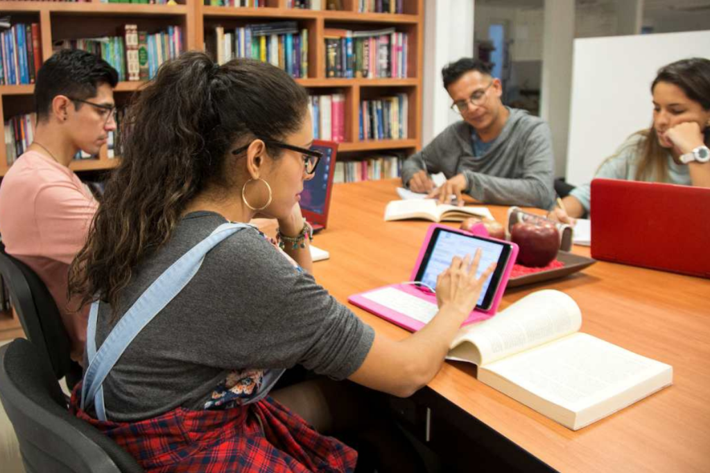 Young people sitting in a library using their laptop computers.